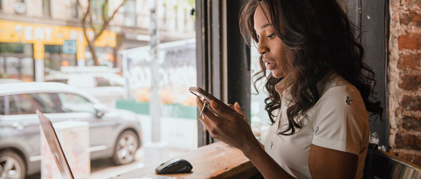 Mujer revisando pagos de clientes en su laptop y celular